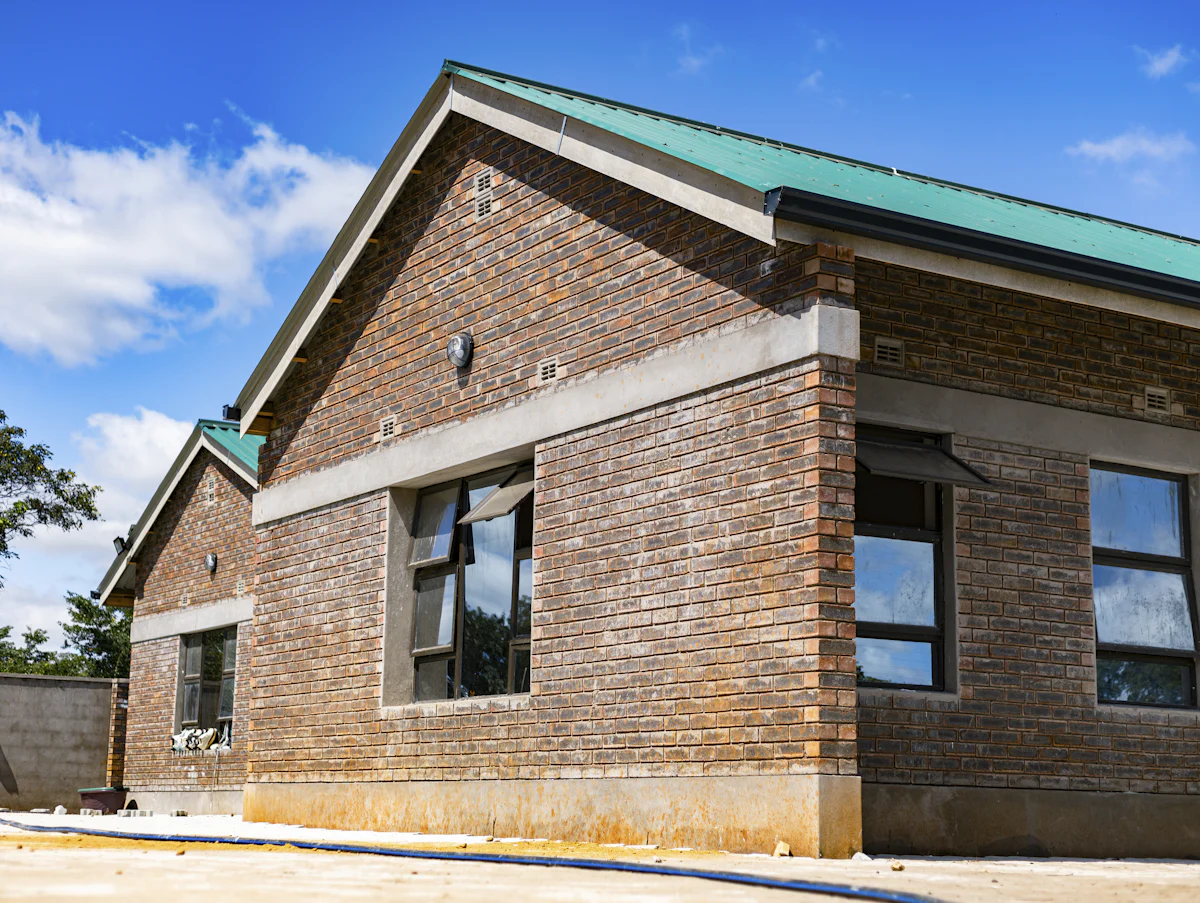 Face-brick house with a green metal roof under construction