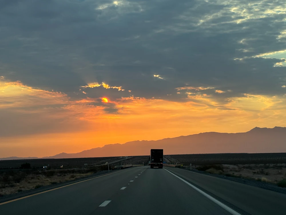Freight truck on an open road at sunset